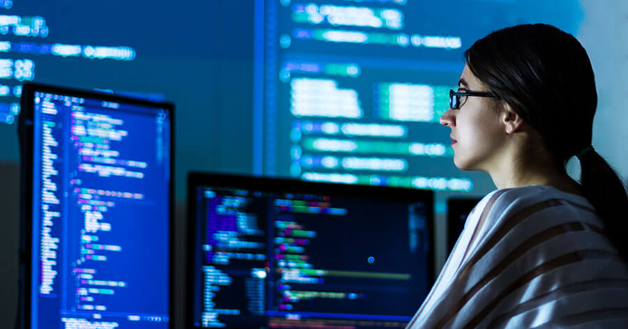 A woman is working in front of multi-screen computer station.
