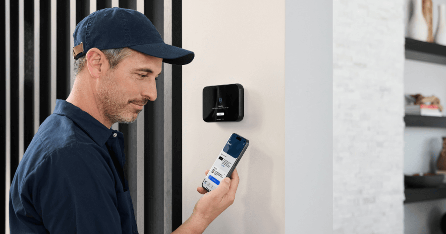 A professional technician is setting up the smart thermostat app on a phone.