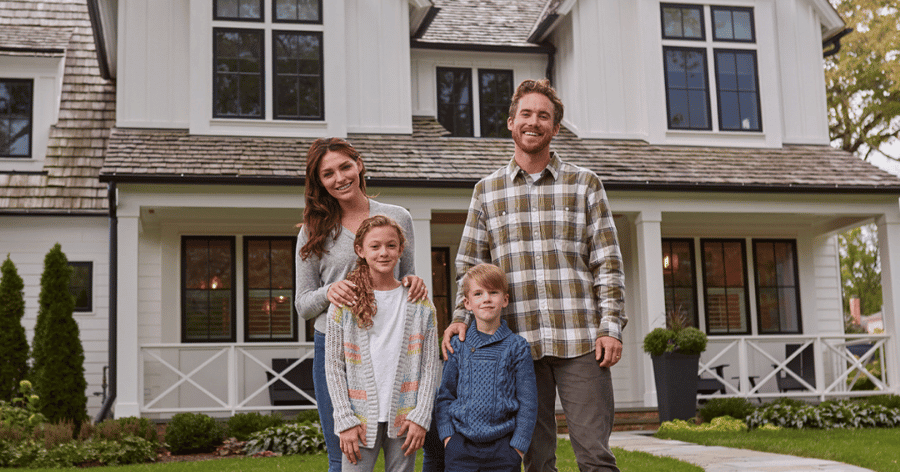 Family of four standing in front of the house