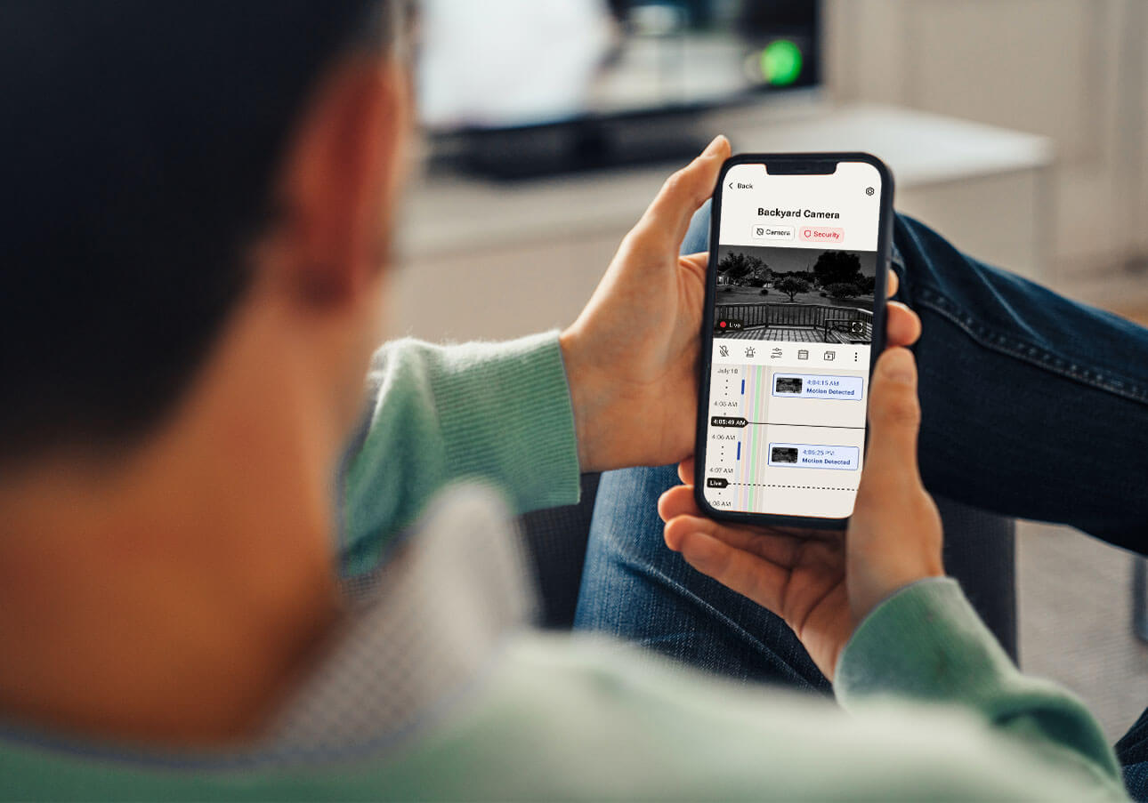 A man views his backyard security camera feed on his smartphone app.