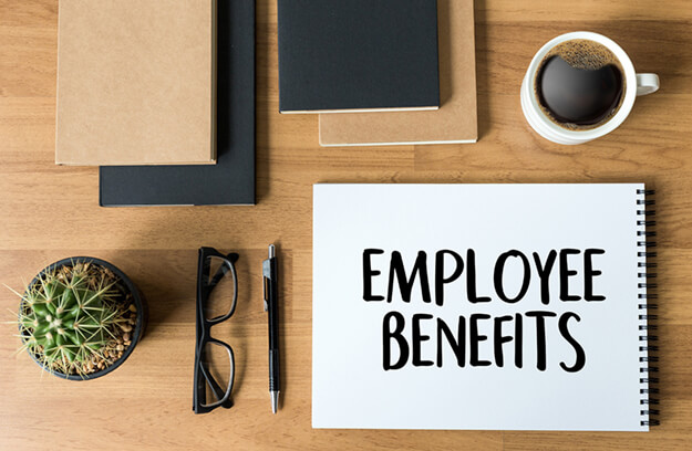 Various desk items and a notepad that reads Employee Benefits