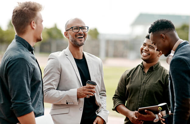 A group of men standing together, laughing.