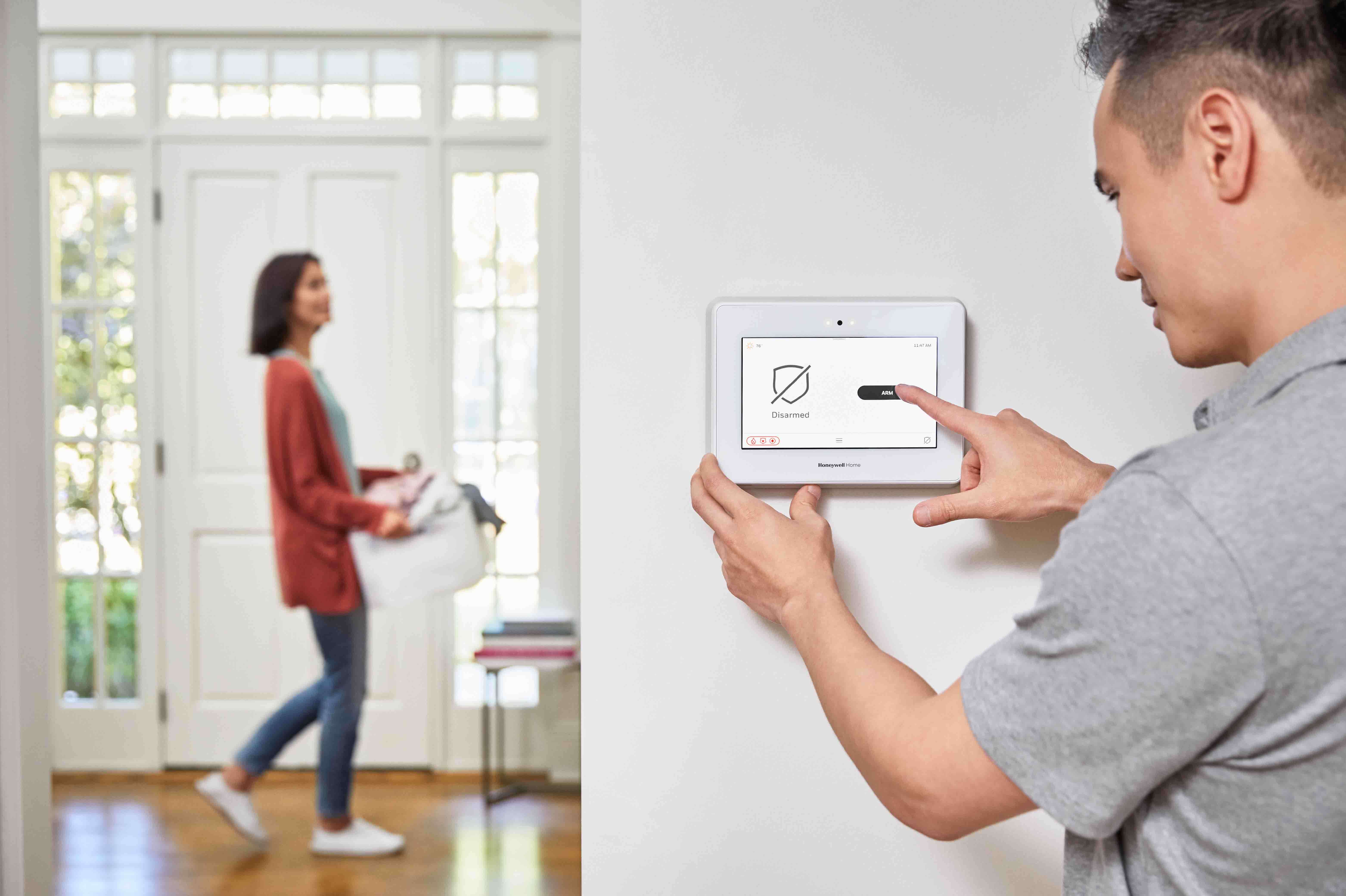 proffessional uses on-wall thermostat, with woman in background